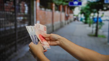 Bir sokak gösteriminde Tayvan dolarları sayan bir adam ve şehir ortamında yatırım temaları açık havada el ele tutuşma banknotları yaratıcı bir şekilde.