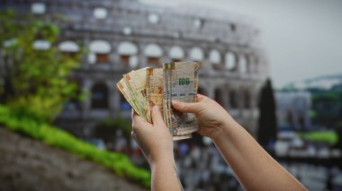Roma kolezyumunun önünde Perulu tabanlar sergileyen bir kadın, şehir merkezinde para değişimi ile kültürlerin karışımını sembolize ediyor..