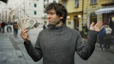 Şehrin hareketli caddesinde elinde İngiliz banknotları tutan İspanyol bir adam şehir ortamında zenginlik ve kayıtsızlık sergiliyor..