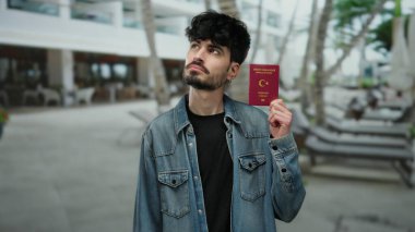 Şehir merkezinde Türk pasaportu taşıyan bir adam modern kasaba sokaklarında seyahat ve kimlik konsepti sergiliyor..