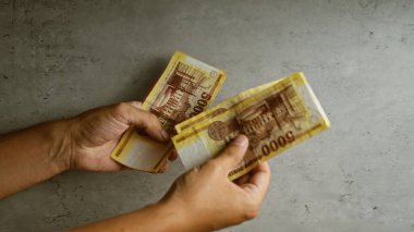 Elleri beton bir arka planda Macar banknotlarını tutuyor..
