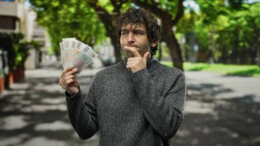 Czech Koruna 'yı elinde tutan İspanyol bir adam şehir sokaklarında finansman sağlıyor, kentsel bir ortamda mali kararlar alıyor..