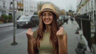 Latin kökenli genç bir kadın, şehir sokaklarında el kol hareketleri yaparak, açık hava ortamlarına güveni gösteriyor..