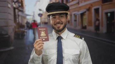 Pilot üniformalı genç bir adam Filipinli bir pasaport tutuyor, canlı bir sokakta açık havada gülümsüyor, seyahat ve havacılık temalarını sergiliyor..