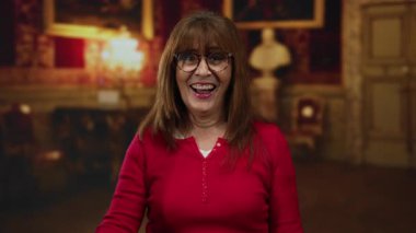 Latin kökenli son sınıf öğrencisi bir kadın müzede gülümseyen bir taş işareti yapıyor. Mutluluk ve kültürel nişan gösterisi yapıyor..