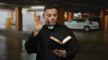 Rahip kılığındaki genç adam kapalı otoparkta bir kitap okuyor. Arka planda bulanık bir araba ile sürpriz yaparak gizemli bir atmosfer yaratıyor..