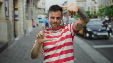 Dövmeli genç adam şehir sokaklarında kırmızı çizgili tişört giyip, eğlenceli ve ilgi çekici bir sahne yaratıyor..