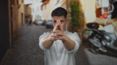 Canlı bir şehir ortamında, sokak ortasında bir silah jestini taklit eden genç adam, mobiletler ve binalar arasında neşeli bir ifade ve şehir yaşam tarzı sergiliyor..