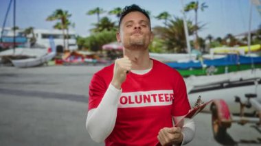 Kırmızı gönüllü gömlekli bir adam sahilde elinde bir panoyla dikiliyor. Palmiye ağaçları ve teknelerin arasında kendine güvenen bir ifade sergiliyor. Açık havada kamu hizmeti yapmayı öneriyor..