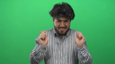 Sakallı genç adam çizgili gömlekli yeşil arka plana karşı olduğunu söylüyor..