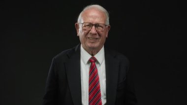 Tecrit edilmiş siyah bir arkaplan üzerinde kıdemli bir adam, düşünceli ve içsel bir tavırla çeşitli duygular ifade ediyor..