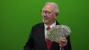 Takım elbiseli kıdemli bir adam bize dolar tutuyor ve canlı yeşil bir arka plana gülümsüyor. Başarıyı ve serveti aktarıyor..