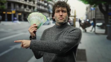 Gri kazaklı İspanyol bir adam işlek bir şehir caddesinde Rus rublesi tutuyor ve şehir ortamında dinamik bir ticaret manzarası yaratıyor..