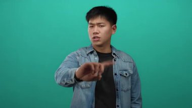 Genç adam, yeşil bir arka plana parmağını sokup, onaylamadığını söylüyor.