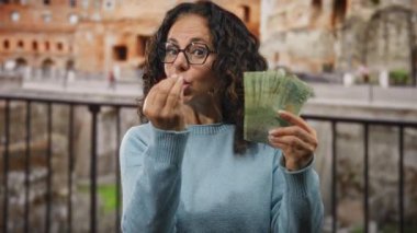 Roma 'da elinde Arjantin pesoları olan bir kadın, Roma harabeleri yakınında sinir bozucu bir ifadeyle, açık bir şehirde turizm, finans ve kültür alışverişi sergiliyor..