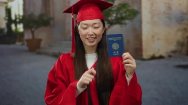 Mezuniyet elbisesi giymiş bir kadın, Kore pasaportunu şehir sokaklarında tutarak eğitim ve seyahatte yeni başlangıçları ve başarıları sembolize ediyor..