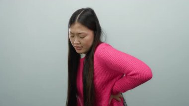 Pembe kazaklı kadın beyaz arka planda sırt ağrısı çekiyor. Ayrı bir ortamda sağlık ve duruş sorunları yaşıyor.