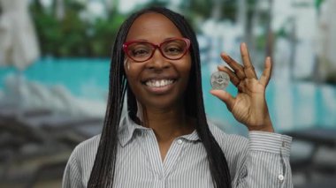 Tatil köyünde elinde havuz başında havuz başında gülümseyen bir kadın açık hava ortamında kripto güveni sergiliyor..