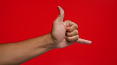 Adamın biri parlak kırmızı arka plana el hareketi yapıyor. Bu da dostça ya da rahat bir iletişim tarzını simgeliyor.