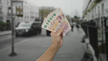 Şehir sokaklarında Arjantin pesoları tutan, şehir yaşamının ortasında canlı para gösteren, ticaret ve finans konularını vurgulayan bir adam..