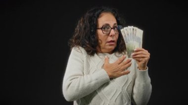 Orta yaşlı bir kadın, elinde siyah arka planda Mısır poundu tutarak şaşkınlık ya da korku duyguları göstererek ürktü..