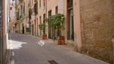 Tarihi binalar ve bitkilerle dolu bulanık Akdeniz sokak manzarası eski bir kasaba ortamında dingin, dağılmış bir atmosfer yaratıyor..