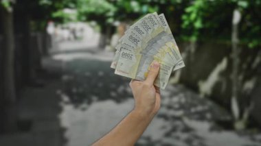 Endonezya Rupiah 'ı elinde tutan adam şehir sokaklarında döviz kurunu ve finansal kavramları ön plana çıkarıyor..