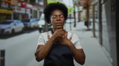 Kalabalık şehir sokağında arka planda araçları olan önlük giymiş bir kadın öksürüyordu. Bu da iş stresi ve kirliliği ön plana çıkaran bir şehir ortamını işaret ediyordu..