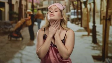 Gece elbiseli bir kadın şehir sokaklarında boğazını tutuyor. Aydınlık bir günde uyku maskesiyle rahatsız görünüyor. Rahatsızlığı ve kentsel yaşam tarzını simgeliyor..