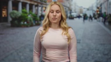 Şehrin arka sokaklarında neşeli bir şekilde poz veren genç sarışın kadın. Bulanık bir şehir geçmişi var. Moda ve canlı bir ifade sergiliyor..