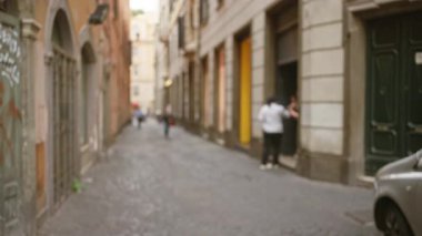 Roma 'nın eski kasabasında, tarihi binalar ve yumuşak Bokeh ışıklandırmalarıyla çevrili kaldırım taşlı bir yolda yürüyen bulanık insanlar..