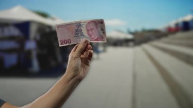 Açık pazarda el ele tutuşan Türk lirası. Arka planda bulanıklık var. Sokak dükkânı dekorunun özünü yakalıyor..