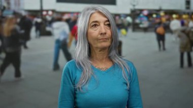 Şehir dışında kalabalık bir sokakta, hareketli insanlarla çevrili, gri saçlı son sınıf öğrencisi kadın, şehir hayatını ve yaş farkını aktarıyor..