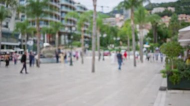 Monako 'nun bulanık lüks caddesinde palmiye ağaçları ve bokeh etkisi ile kalabalık kalabalık bir şehir atmosferi yaratıyor..