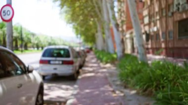 Açık hava bulanık görüntüsü araba yolu ağaçları kaldırım hız tabelası ve güneşli bir günde bina.