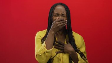 Ağzı kaplayan kadın kırmızı arka planda sarı bluz giymekten rahatsız görünüyor. Duygularını ve renklerini canlı bir şekilde aktarıyor.