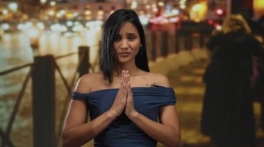 Elleri sıkıca bağlı dua eden bir kadın gecenin bir yarısı bulanık ışıklarla şehir dışında huzur içinde..