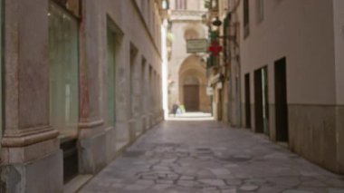 Bulanık yayalar ve güneş ışığı altındaki tarihi Akdeniz mimarisi ile eski şehir caddesi dar sokaklar ve odak noktasından uzak figürler sergiliyor..