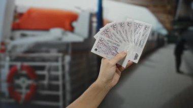Deniz kıyısındaki bir yolcu teknesinde bulanık bir geçmişi olan bir adam seyahat ve finans temalarını öneriyor..