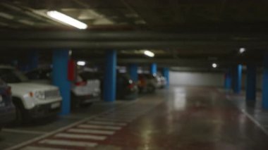 Loş ışıklandırılmış bir ortamda arabalarla dolu bir yeraltı otoparkının bulanık görüntüsü, bokeh etkisi gösteriyor..