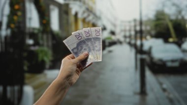 Isvicre Krone, yağmurlu bir şehir caddesinde açık havada el ele tutuşarak, şehir içi harcamaları ve insanların halka açık bir ortamda yaptığı mali işlemleri gösteriyor..