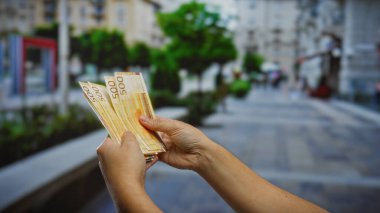 Bir şehir caddesinde Norveçli kroner 'ı tutan eller, şehir dışındaki iş ve yatırımı sembolize ediyor..