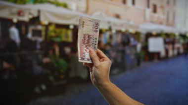 Kentsel sokak ortamında el ele tutuşan Tayvan Doları. Bulanık restoran terası geçmişi şehir çevresindeki yatırımları ve iş yerlerini gösteriyor..