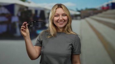 Güneşli bir günde arka planı bulanık bir şekilde elinde bardak tutan bir kadın..