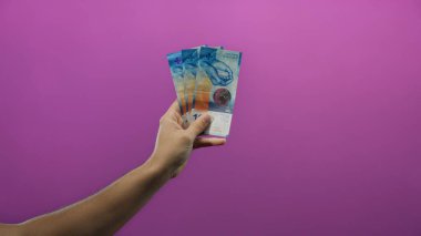 İzole edilmiş mor arka plan üzerinde İsviçre frangı banknotları, kişisel ve renkli bir dokunuşla para, finans ve zenginlik vurgulanıyor.