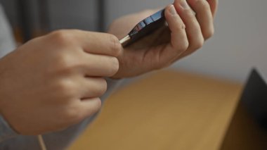 İş yerinde akıllı telefonu elinde tutan, modern ofis ortamında bağlantı kurmaya odaklanan, genç yetişkinler arasında teknoloji kullanımını gösteren bir adam.