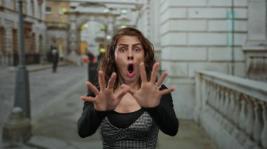 Şok olmuş gibi görünen bir kadın, şehir merkezinde korku ve şaşkınlığı ifade ediyor..