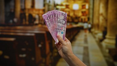 Kilisenin içinde Filipinli pezoların el ele tutuşması, iş, finans ve kültür mirasına odaklı dini bir bağlamda yatırım ve bağışı sembolize ediyor..