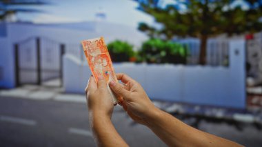 Şehir sokaklarında 20 Filipinli peso banknot tutan bir adam, şehir ortamında yatırım ve işi temsil ediyor..