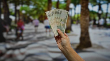 Kalabalık bir şehir sokağında elinde para tutan adam, Birleşik Arap Emirlikleri 'ndeki iş ve para alışverişini sembolize ediyor..